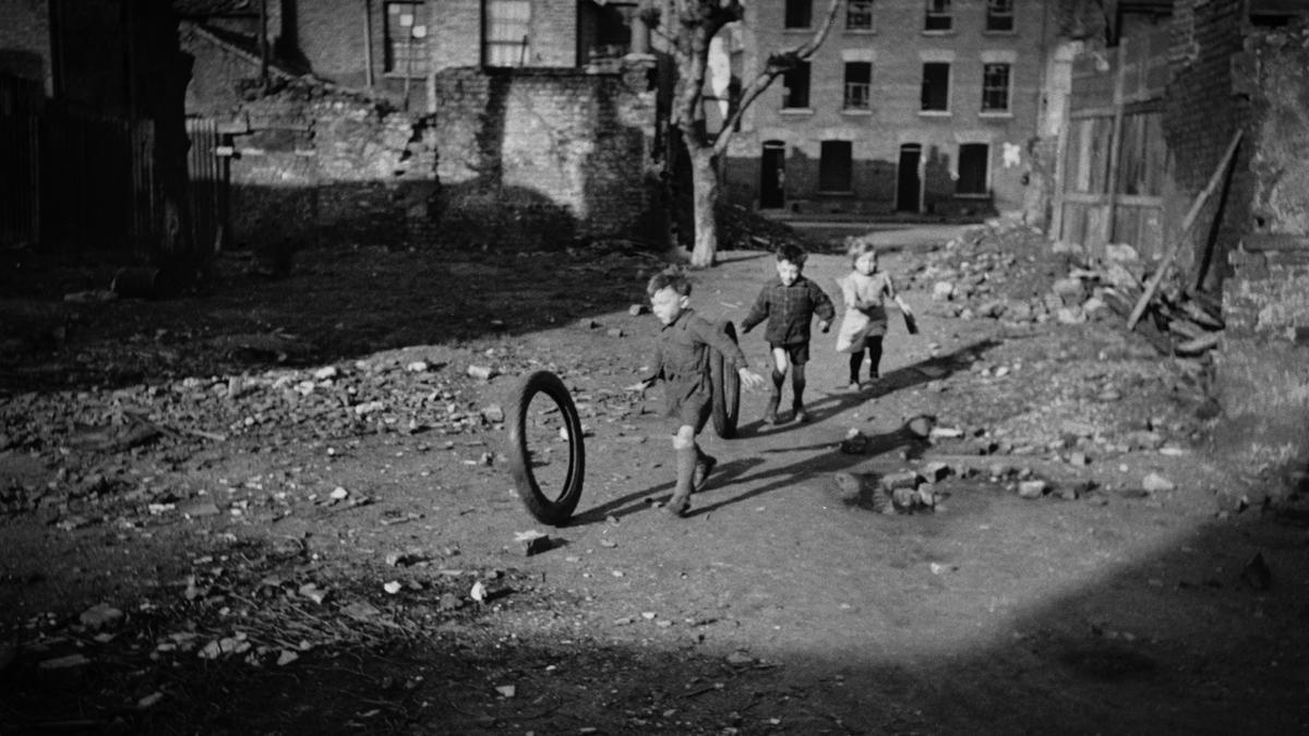 Children playing with a tire in an urban street